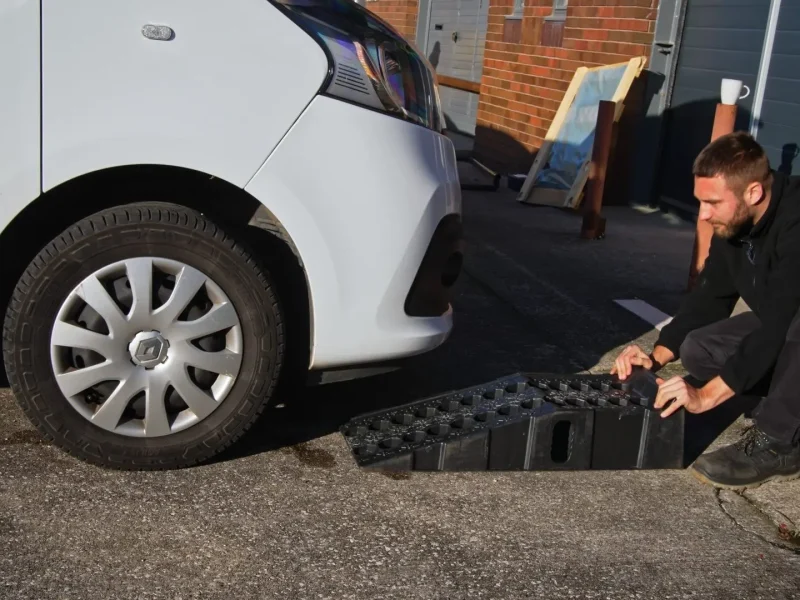 Technician at work beside a customer's van on a driveway