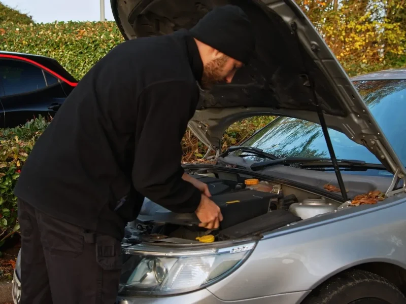 Technician working at the open bonnet of a customer's car